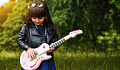 young girl with flowers in her hair playing an electric guitar